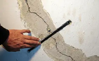 A wall with a large crack is being inspected by a professional in Pueblo, CO